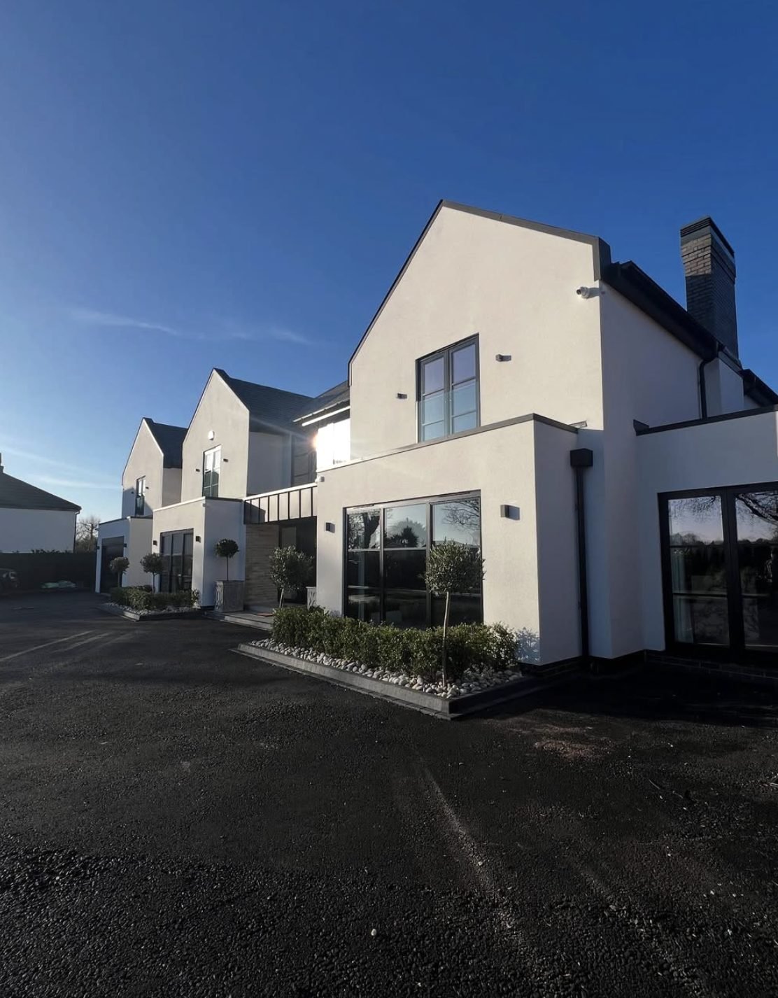 Pair of modern houses in smooth white render with dark grey frames
