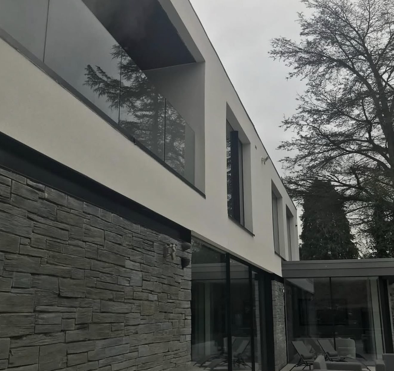 Smooth render carried above a stone-clad ground floor on a contemporary elevation