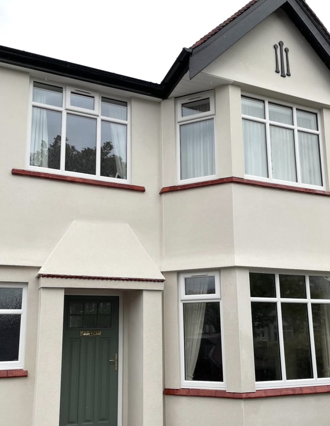 Cream rendered 1930s semi with white windows and red tile cills